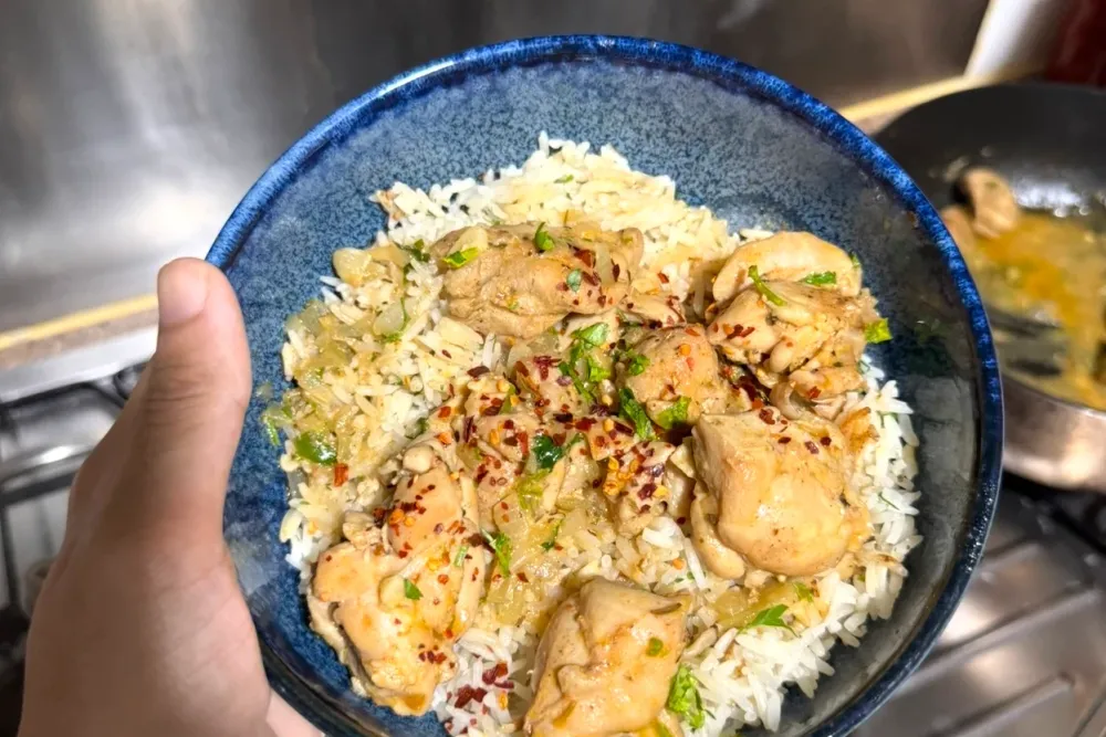 Greek lemon chicken and rice — golden chicken thighs in a lemon sauce over rice with herbs, in a blue bowl